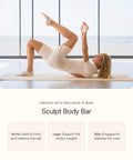 Woman exercising with sculpt body bar in light workout attire on a yoga mat by a window, focusing on balance and stability.