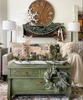 Rustic living room decor with green table, deer ornaments, wreath, and wall clock.