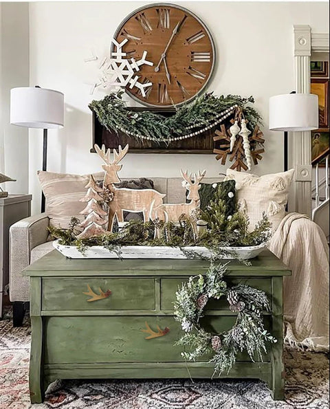 Rustic living room decor with green table, deer ornaments, wreath, and wall clock.