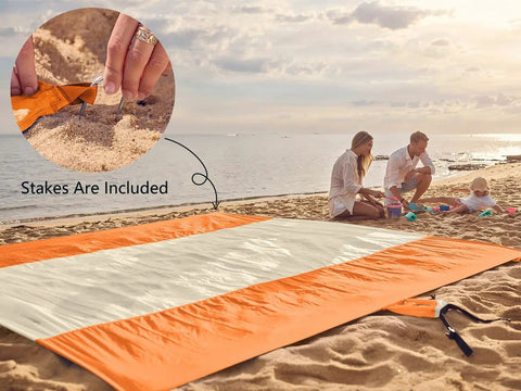 Family using Sandproof And Waterproof Beach Blanket 7x7 Ft Extra Large Mat With Stakes on sandy beach, focusing on included stakes.