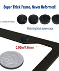 Close-up of matte black aluminum license plate frame corner with matching black screw caps and comparison to coin thickness.