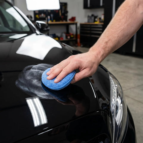 Hand using Beast 20 Pack Microfiber Wax Applicator Pads 5 Inch Blue Foam Car Wash Sponge for car waxing and polishing