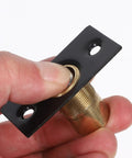 Adjustable Door Ball Catch With Invisible Design, stainless steel with black finish, held between fingers displaying strike plate