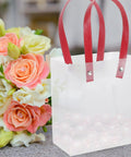 Lightweight Handheld Party Bags With Easy Handle Design 10 Pack Made of Clear PP Material Go to Gift Packaging for Birthday and Wedding Favors Party Supplies, showing red handles and a bouquet background