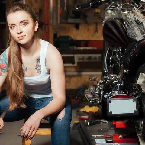 Person working in garage next to bike with Two Pack Stainless Steel Motorcycle License Plate Frames In Black Finish on floor.