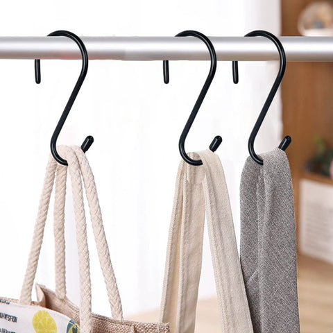 4 black vinyl-coated S hooks hanging bags and towels on a rod for organized storage. 12 Pack Four And A Half Inch Vinyl Coated S Hooks Heavy Duty Non Slip Closet Hooks For Hanging Jeans Clothes Towels Plants Pots Cups Pan And More Durable Rust Resistant Rubber Coated For Safe Scratch Free Storage.