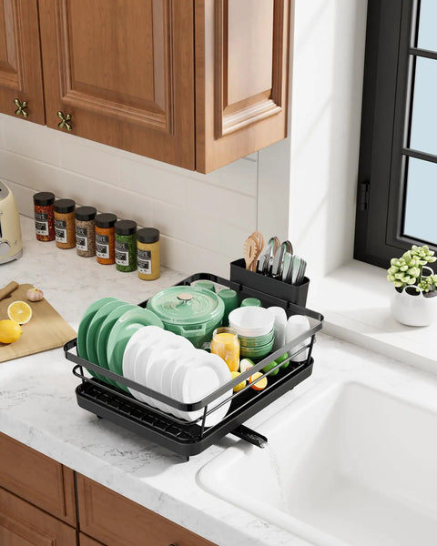 Compact Dish Drying Rack For Kitchen Counter Black Space Saving Drainer holds plates and bowls on a countertop next to a sink.