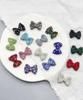 60Pc Glossy Black Disco Ball Beads With Sparkly Rhinestone Perfect for Diy Jewelry Crafting Dazzling Necklace Charms or Bracelet Spacers Add Dope Swag to Your Creations 21.5X30Mm Size for Ultimate Bling Effects and Vibe Ups with colorful rhinestone bow-shaped beads on a plate.