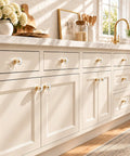 Six Pack Swanky Clear Faceted Glass Cabinet Knobs With Trendy Gold Alloy Base on cream kitchen cabinets with natural lighting.