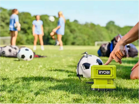 Cordless Tire Inflator Kit With 18V 2 Ah Battery And Charger, Digital Gauge inflating a soccer ball on grass field.
