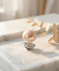 Close-up of a 25Pcs No Sew Faux Pearl Brooch Pin on a marble surface, showcasing its chic design and metal clip.