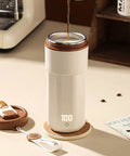 Self Heating Coffee Mug With Quick Temperature Display And Totally Spill Proof Lid on a table with coffee being poured.