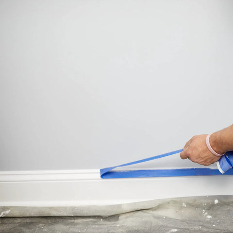 Applying Blue Painters Tape With PaintBlock For Sharp Lines on painted wall and wood trim before painting.
