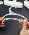Hands holding a white plastic hanger from the Set Of 50 White Plastic Hangers For Retail Display And Home Closet Organization