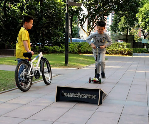 Children playing with Extra Wide Kids Jump Ramp For Skateboard, Scooter, Bike, BMX, RC Car And Dirt Bike 23.62 Inch Wide outdoors.