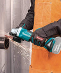 Person using 18V LXT Brushless Cordless Paddle Switch Cutoff And Angle Grinder Four And One Half Inch to cut metal pipe