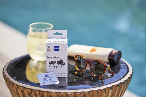 Front view of ZEISS Lens Wipes box for sunglasses cleaning (30 wipes) with a small sachet beside tortoiseshell sunglasses.
