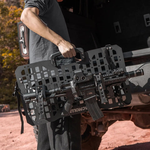 Person holding 2 Pack Tactical Gun Rack For MOLLE Panels Automotive Rifle Holder For Cars And Trucks with attached rifle