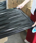 Heavy Duty Black Stretch Wrap 1500 Ft Roll With Hand Saver Handles 15 Inch Wide 70 Gauge Shrink Film being handled.