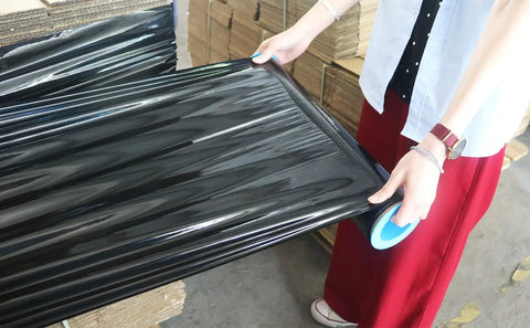 Heavy Duty Black Stretch Wrap 1500 Ft Roll With Hand Saver Handles 15 Inch Wide 70 Gauge Shrink Film being handled.