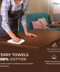 Person cleaning table with cotton terry towel, showcasing 60 Pack Cotton Terry Towels 14 By 17 Inches Highly Absorbent Cleaning Rags For Kitchen Bar And Restaurant Use Durable White Commercial Grade Ideal For Dishwashing Mopping And General Commercial Cleaning