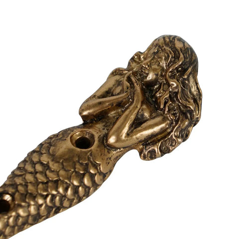 Close-up of antique aqua mermaid shaped metal wall hook from set of 2, part of beachy coastal decor, showing detailed craftsmanship.