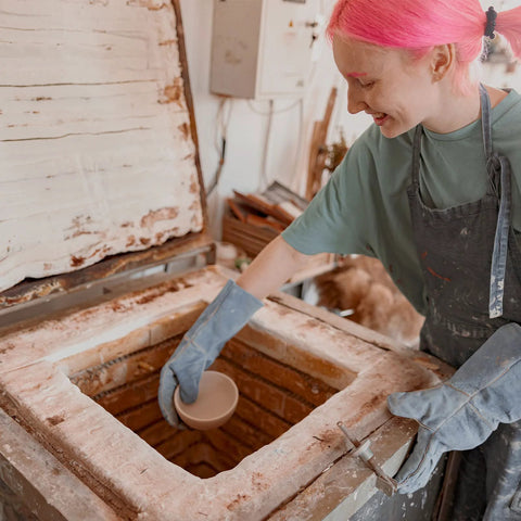 White ceramic fiber insulation blanket inside a brick fireplace, being installed by a person wearing gloves