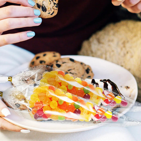 Cone Treat Bags 500 Pack Heat Resistant OPP Material filled with colorful candies on a plate with cookies.