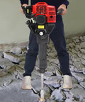 Person operating Gas Powered Demolition Jack Hammer 52cc 2 Stroke With Pointed And Flat Chisels on concrete debris