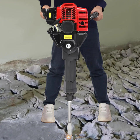 Person operating Gas Powered Demolition Jack Hammer 52cc 2 Stroke With Pointed And Flat Chisels on concrete debris