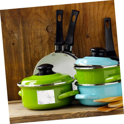 Colorful kitchenware set including green and blue pots with lids and black-handled frying pans against wooden background.