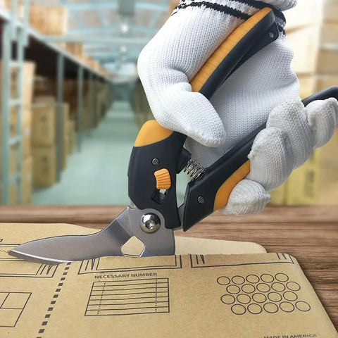 9 Inch Heavy Duty Multipurpose Scissors With TPR Handle cutting cardboard in a workshop, showcasing serrated blades for easy cutting.