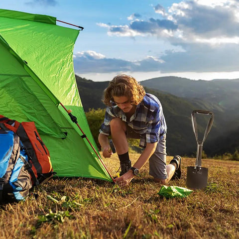 Person camping with a Compact 18.5 Inch Folding Camping Shovel With High Carbon Steel Blade Lightweight Ergonomic Design Portable Digging Shovel
