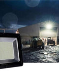 Led Flood Light, IP66 Waterproof Super Bright Security Lights illuminating outdoor work area at night with machinery nearby.