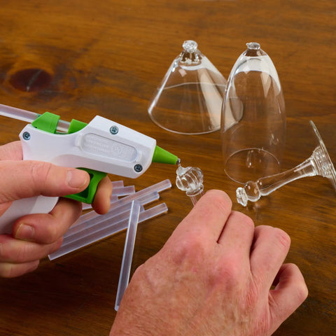 Person using High Temp Mini Hot Glue Sticks 4 Inch 200 Count Two Pack for crafting glass on wood surface