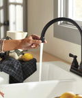 Person using Elmhurst Two-Handle Kitchen Faucet With Twist Aerator, Deck Mount, Oil Rubbed Bronze, High Arc Gooseneck Spout