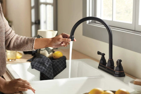 Person using Elmhurst Two-Handle Kitchen Faucet With Twist Aerator, Deck Mount, Oil Rubbed Bronze, High Arc Gooseneck Spout