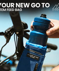 Rider placing bottle into Cosmic Blue 1.6L Adjustable Handlebar Stem Bag With Zipper Pocket Weather Resistant Ripstop Secure Cord