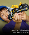Child holding Technic Yellow Motorcycle Building Kit For Kids 7 and Up with Realistic 3 Piston Engine and a Working Rear Wheel