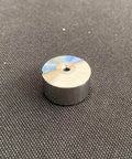 Waterjet check valve seat, cylindrical metal part with central bore; silver top, dark body