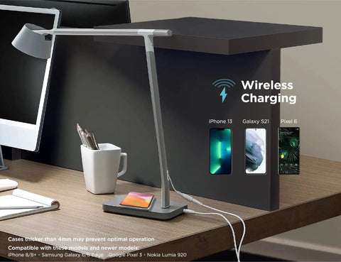Verve Designer Desk Lamp With Qi Wireless Charger on office desk showing wireless charging capability with three phones.