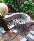 Person constructing a foundation for 8KW To 12KW Single Phase Axial Flow Hydroelectric Generator For High Flow Low Head Hydropower At 230V An Off Grid Power Kit For Homes And Small Farms Right Now with concrete blocks in a garden setting.