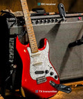 Red electric guitar with UHF Wireless Guitar System With Rechargeable Transmitter And Receiver on amplifier, gig setup.