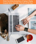 Person typing on a laptop with 2 Pack Wrist Wraps For Carpal Tunnel Relief And Pain Prevention, cat nearby, and coffee cup on desk.