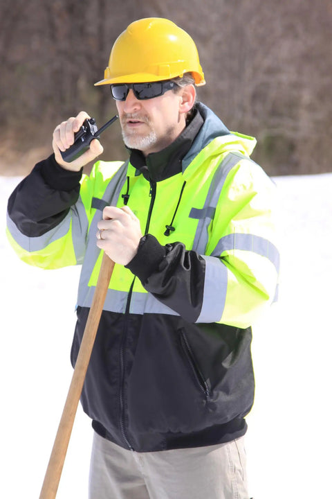 Worker in Waterproof Class 3 Hi Vis Lime Fleece Bomber Safety Jacket With Detachable Hood using radio on job site