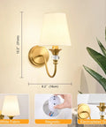 Battery Operated Wall Sconces Set of 2,Rechargeable Wireless Wall Sconces with 10000mAh RGB Dimmable Bulb and Remote,15 Colors Cordless Wall Lights for Bedroom,Bathroom,Living Room & Hallway(Gold) mounted on wall with white fabric shade.