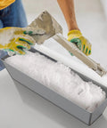 Person using Heavy Duty 12 Inch Stainless Steel Mud Pan For Drywall, Watertight Reinforced Pan With Tapered Sides for mixing drywall mud.