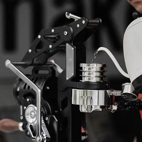 Hand Cranked Espresso Maker Boasting A 58mm Pro Brew Group And Adjustable Pressure Levers, pouring water into portafilter.