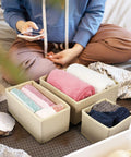 6 Piece Underwear Drawer Organizer Set Features Fold Flat Storage Bins featuring rolled towels in beige bins on a bed.