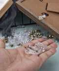 Top Tier 50 Pack Cabinet Glass Retainer Clips And Gold Screw Kit For Easy Door Installation and Rock Solid Home Setup shown in hand.